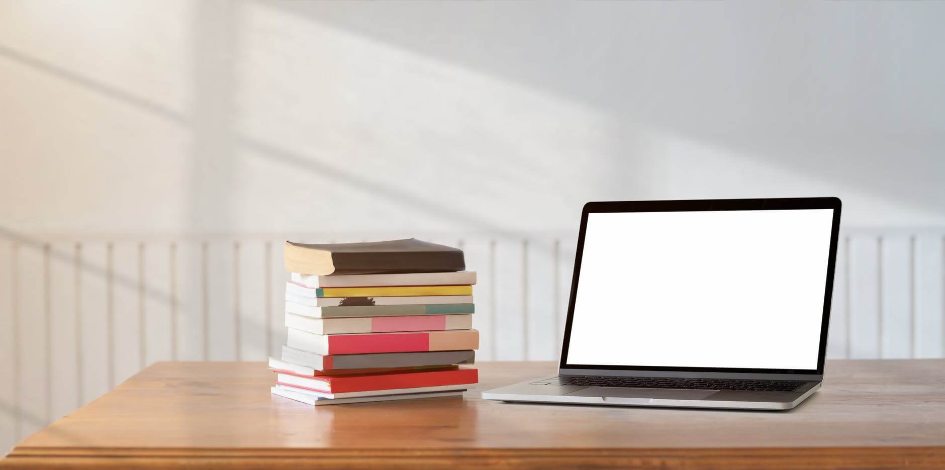 black laptop computer on brown wooden table beside books